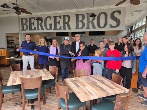Ribbon-cutting gathering in front of the Berger Bros. sign in the expanded room